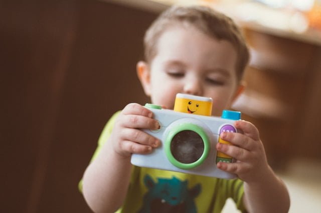 Toddler holding a camera. Against the Niche at all Odds