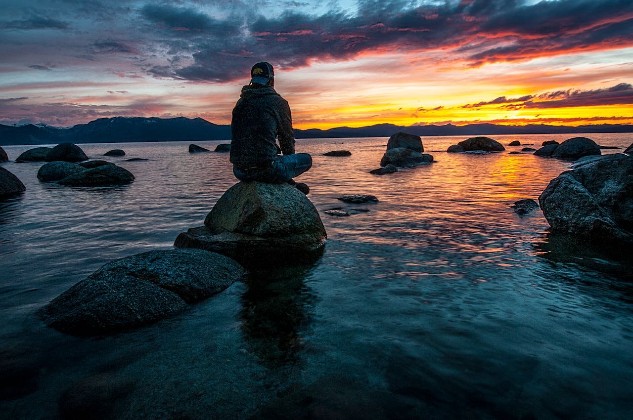 Person sitting on rocks overlooking the ocean.