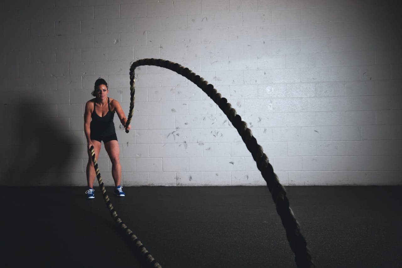 Women utilizing battle ropes in a dark setting.