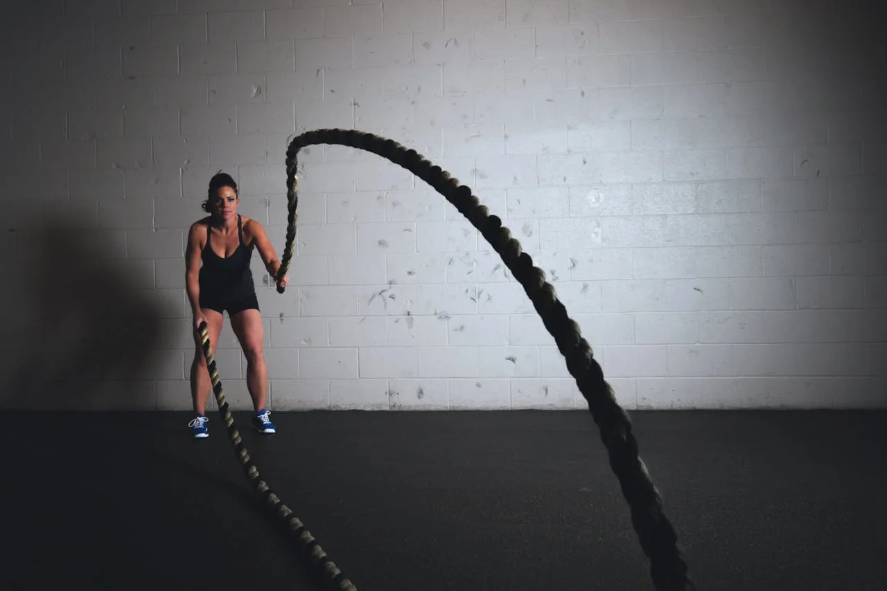 Women utilizing battle ropes in a dark setting.